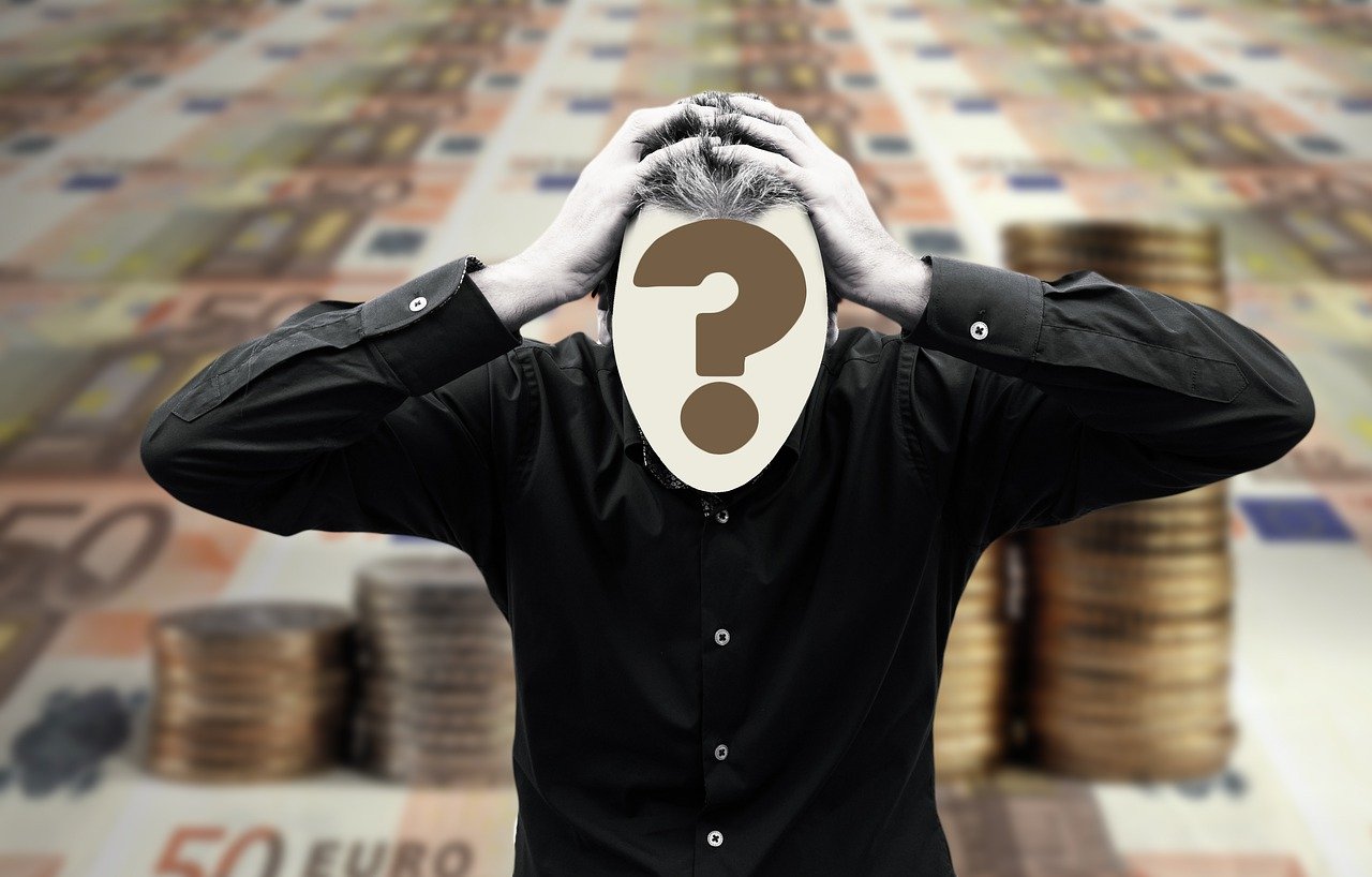 A person in a black shirt clutching their head, with a large question mark obscuring their face, stands against a background of euro banknotes and stacked coins.