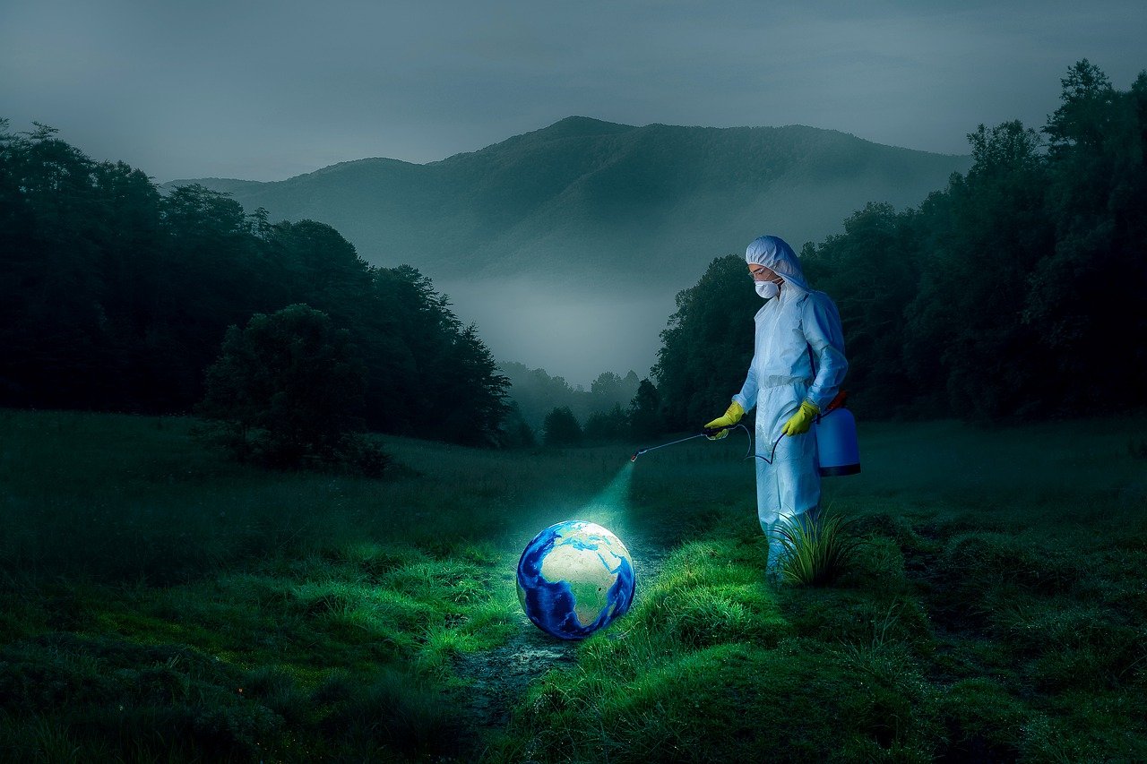 A person wearing a full hazmat suit and yellow gloves stands in a dimly lit forest at night, spraying disinfectant onto a glowing, miniature Earth resting on the ground. The surreal scene highlights themes of human intervention, environmental control, bio-engineering, climate anxiety, and the belief that technology can “fix” the planet.
