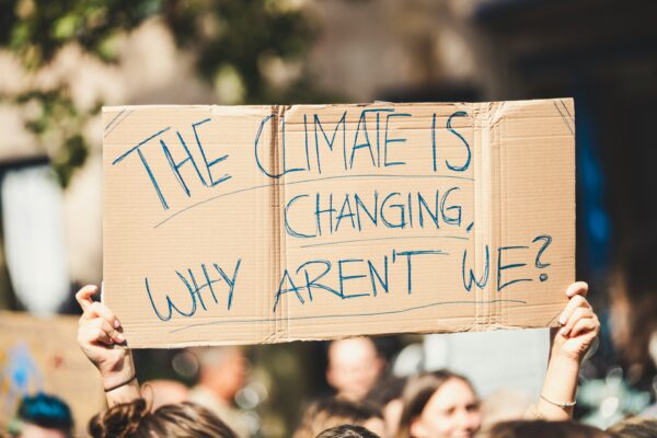 An activist holds up a sign that reads "The Climate is Changing Why Aren't We"