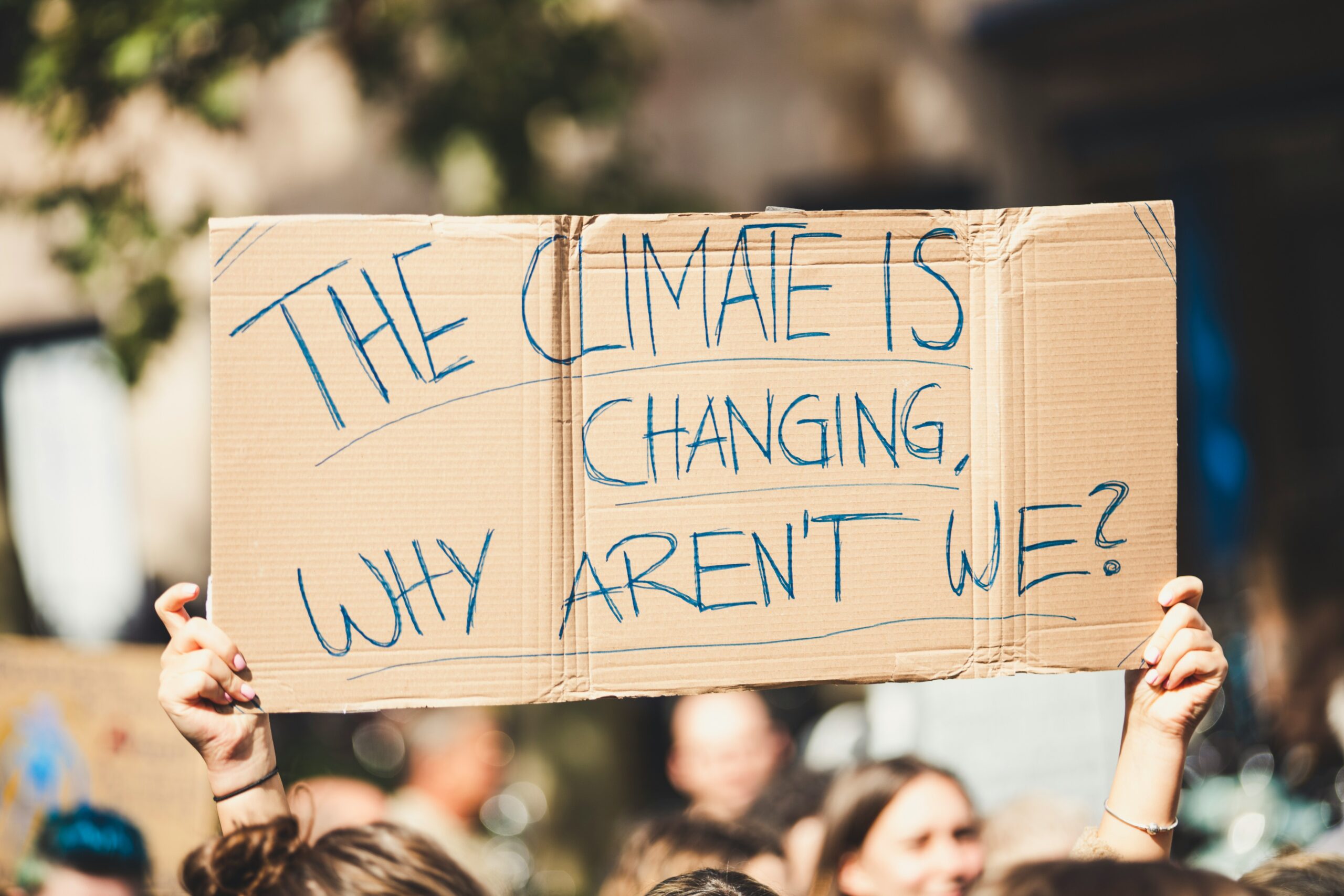 An activist holds up a sign that reads "The Climate is Changing Why Aren't We"