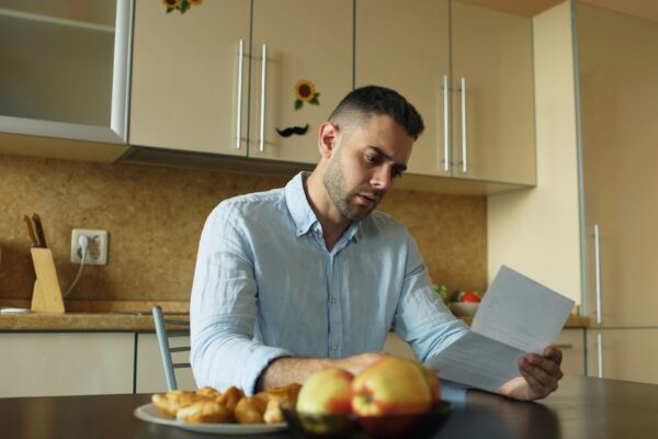 Man Stares With Stress at His Bills
