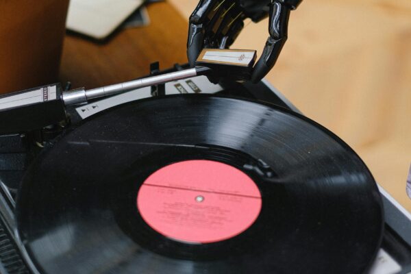 A robotic hand lowering the needle onto a vinyl record player, symbolizing artificial intelligence interacting with traditional music technology and how AI Is reshaping the music industry