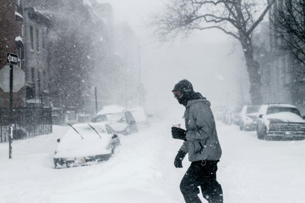 Person walking in heavy snowfall, showing extreme winter weather at work.