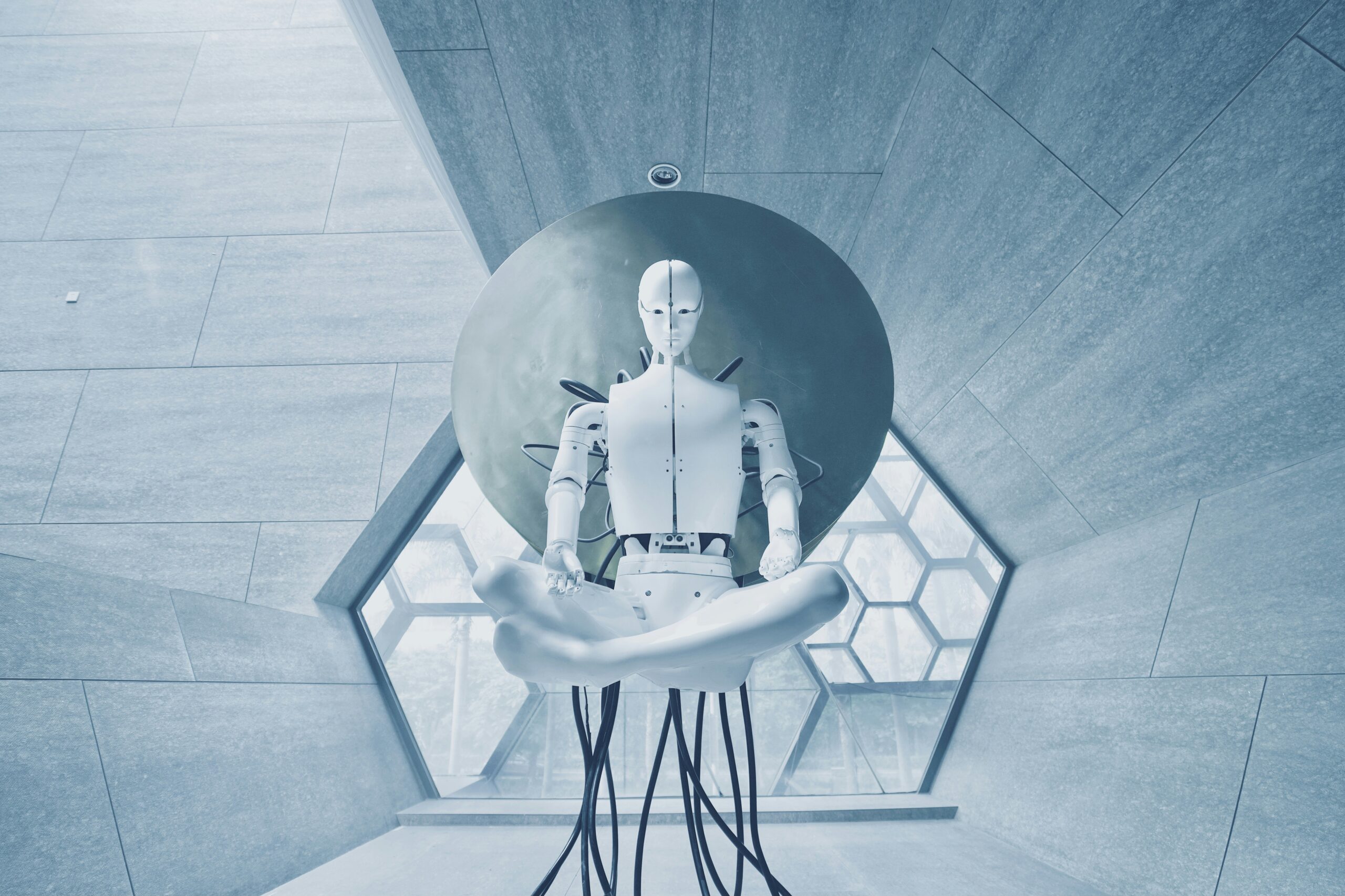White Sci-Fi robot with a cables coming out of it sitting meditating