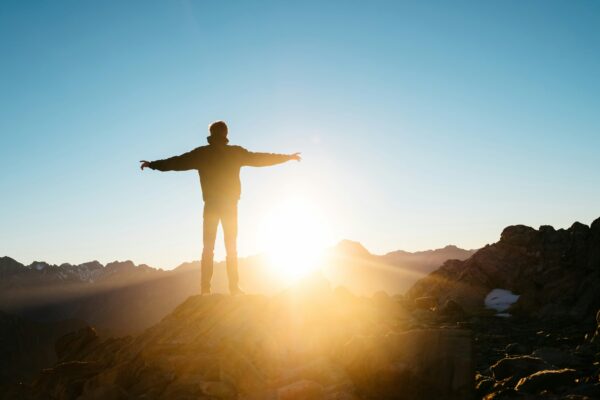 Freedom shown by a person standing in the sunrise with their arms stretched wide