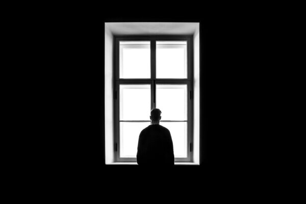 Silhouette of a person by window. This person seems lonely.