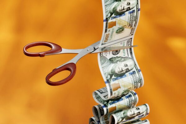 Scissors cutting rolled money bills a metaphor for tax cuts.