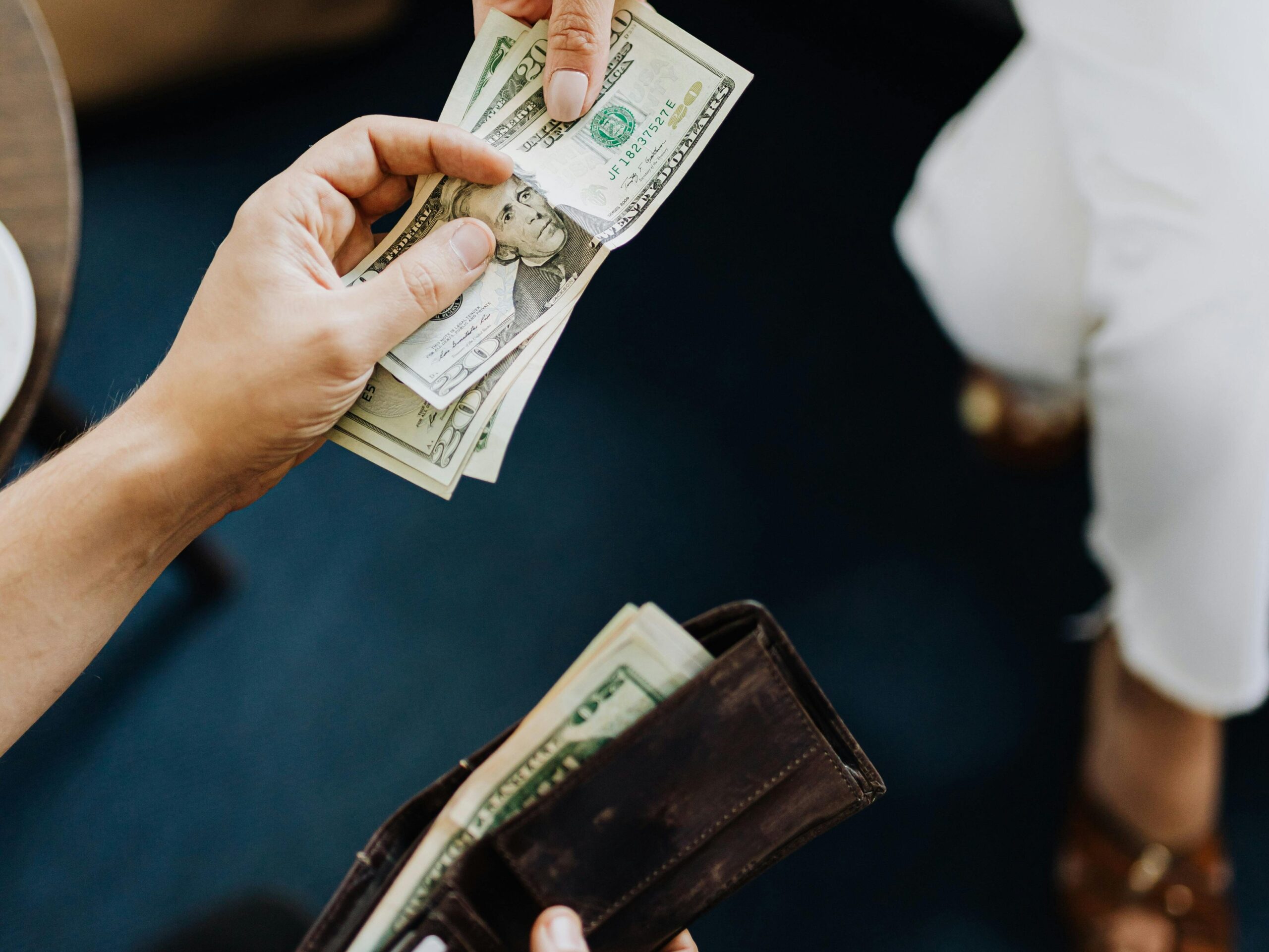 Close-up of hands exchanging cash, representing a financial transaction or payment.