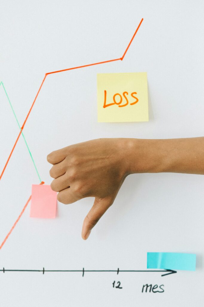 Hand showing thumbs down in front of graph indicating financial loss concept during a recession.