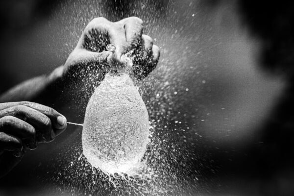 Captivating moment of a water balloon explosion captured in monochrome, showcasing motion and texture.
