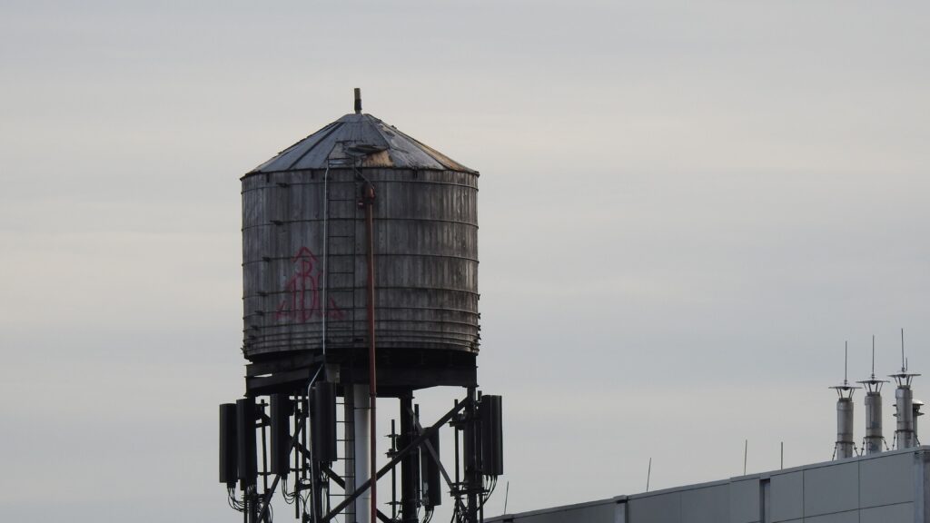 A metal water tank stands prominently on a rooftop against a clear sky.