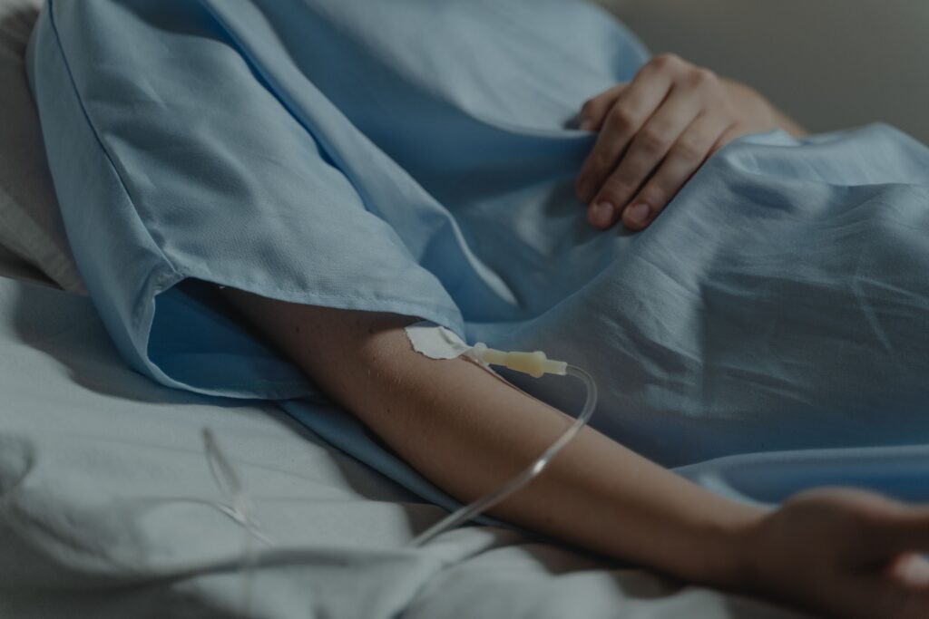 A woman with an IV in her arm in a hospital gown getting treatment for illness or illnesses.