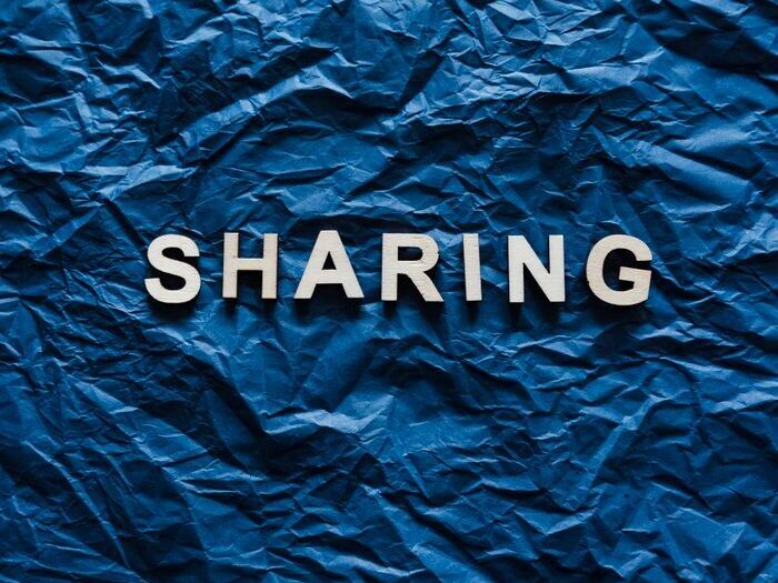 Crumpled blue paper with the word 'Sharing' conveying a conceptual theme.