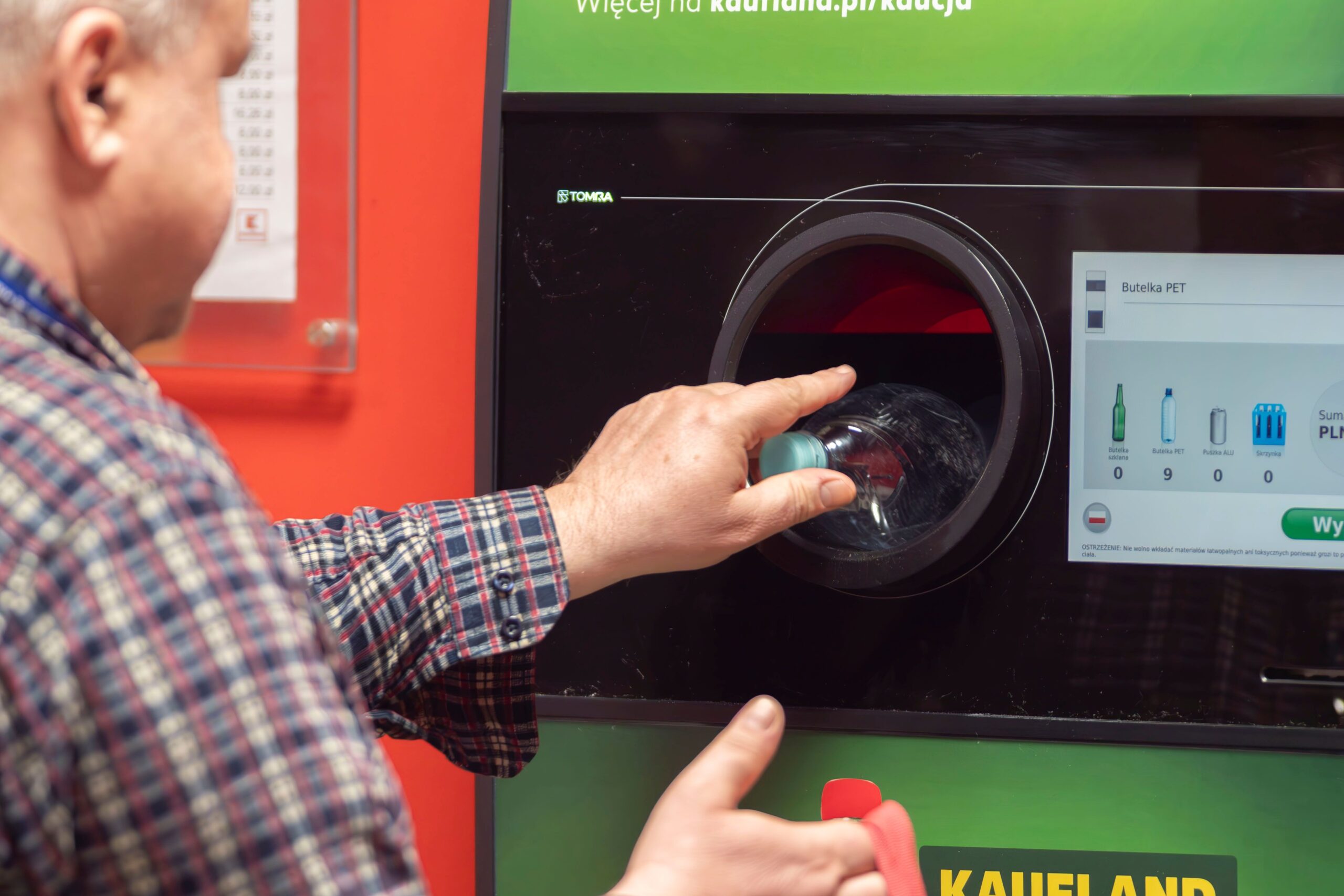 A man recycling plastic bottles at a reverse vending machine in Kaufland, Wrocลaw, Poland.